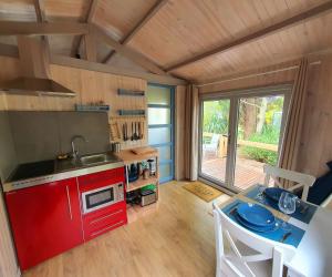 a kitchen with red cabinets and a table with a sink at Adorable chalet avec jacuzzi privatif in Aix-en-Provence