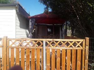 a wooden fence in front of a house with a red umbrella at Un petit coin de paradis in Les Arcs sur Argens
