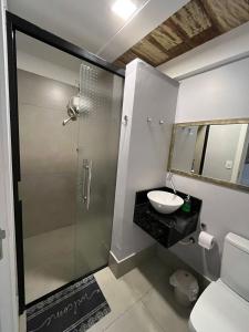 a bathroom with a glass shower and a sink at Estúdio Central 3 in Cascavel +11 photos