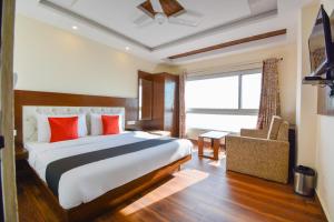 a bedroom with a large bed with red pillows and a window at Hotel Valley Vista in Mussoorie