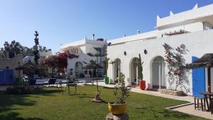 une cour d'un bâtiment blanc avec des plantes dans une cour dans l'établissement Villa Daba, à Ghazoua