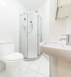 ein weißes Bad mit einer Dusche, einem WC und einem Waschbecken in der Unterkunft City Rooms in London