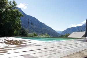 a swimming pool with mountains in the background at Très bel appartement, Parc national des Écrins, piscine et terrasse in Les Vigneaux