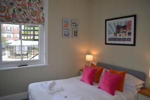 Schlafzimmer mit einem Bett mit rosa Kissen und einem Fenster in der Unterkunft St George's Guest House in York
