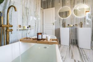 Serenity Prague Villa with garden jacuzzi في براغ: حمام مع حوض ومرآتين