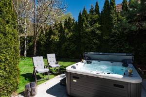 a hot tub in a yard with two chairs at Serenity Villa Prague with Garden and Jacuzzi in Prague