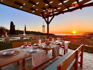 a table set for dinner with a sunset in the background at Luxury Villa Makris with private heatable pool in Kavvadádes