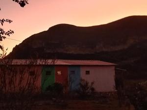 un pequeño edificio con una montaña en el fondo en Pousada Serra Aquarela - Mini casas en Ibicoara