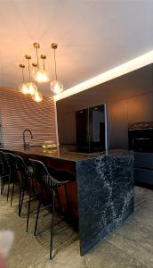 una cocina con un gran mostrador negro con sillas negras en Luxury Aparment 5 room 2 minutes from the beach, en Bat Yam
