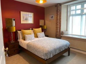 a bedroom with a bed with yellow pillows and a window at The Lantern Townhouse in Dingle