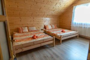 a room with two beds in a wooden cabin at Bucsin Kulcsosház in Joseni