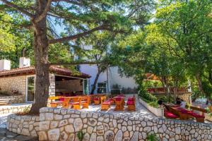 un patio con mesas y sillas bajo un árbol en Rooms and Restaurant Danica en Povile