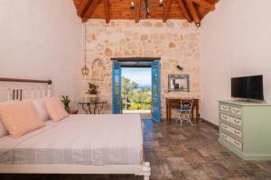 a bedroom with a bed and a television and a table at Strofilia Stone Residences in Volímai