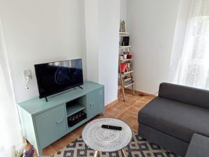 a living room with a couch and a flat screen tv at O'Eirado Playa de Quenxe in Corcubión