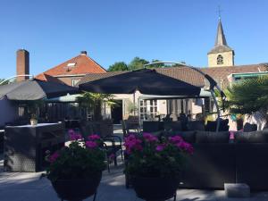 un patio con mesas y sillas con flores y sombrillas en Hotel Restaurant Cafe Houben, en Nunhem