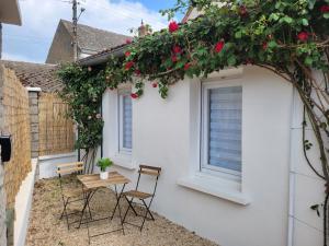 un pequeño patio con sillas y una mesa con flores en Studio cosy Bienvenue chez Elle en Saint-Denis-de lʼHôtel