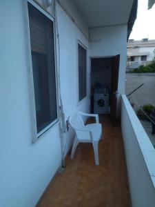 einen weißen Stuhl auf einem Balkon mit einer Waschmaschine in der Unterkunft Casa Poggio in Cagliari
