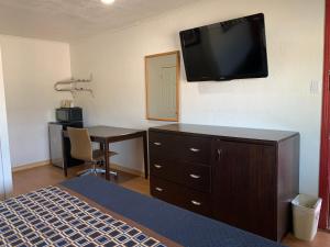 a bedroom with a bed and a desk with a television on the wall at Budget Inn in Memphis