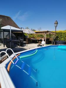 a blue swimming pool with a table and an umbrella at Loft dans longère à la campagne 