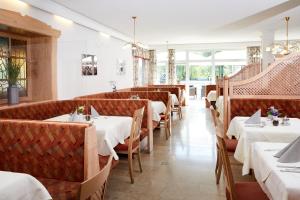 a restaurant with tables and chairs with white tablecloths at LACUS Hotel am See in Weissensee