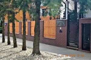 a brick fence with a gate and some trees at Dom Stegny in Warsaw