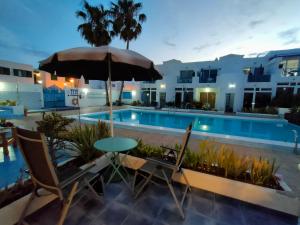 a patio with a table and chairs and a pool at BLU in Puerto del Carmen