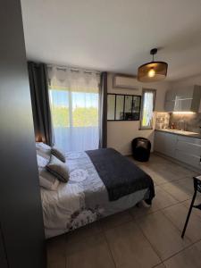 a bedroom with a bed and a kitchen with a window at LE MONICA in Narbonne