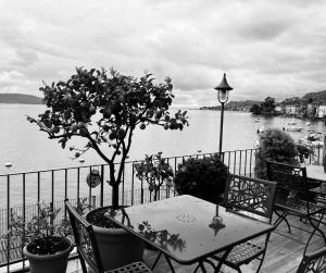 een tafel en stoelen op een balkon met uitzicht op een waterlichaam bij Hotel Garnì Bartabel in Gargnano