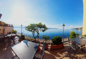 een balkon met tafels en uitzicht op het water bij Hotel Garnì Bartabel in Gargnano