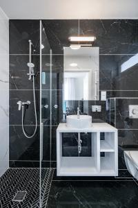 a black bathroom with a sink and a shower at W Starym Porcie in Krynica Morska