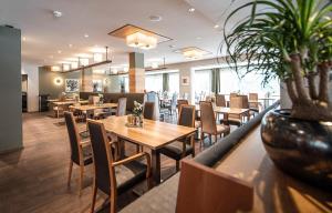 a restaurant with wooden tables and chairs and plants at Vitalpina Hotel Waldhof in Rablà