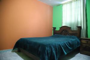 1 dormitorio con paredes de color verde y naranja y 1 cama en Hotel la Cabaña, en El Cocuy