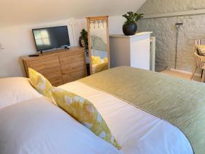 a bedroom with a bed and a flat screen tv at The Loft in the Malt Barn Chipping Campden in Mickleton