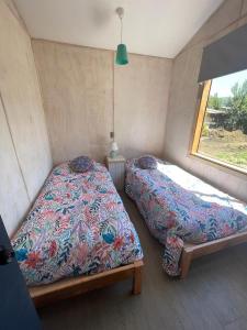 two beds in a small room with a window at CASA VISTA CORRAL in Malalcahuello