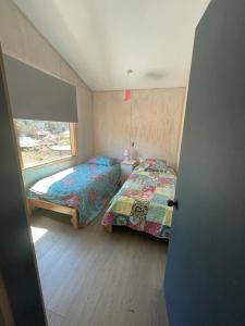 a small bedroom with two beds and a window at CASA VISTA CORRAL in Malalcahuello