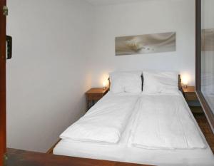 - un lit blanc dans une petite chambre avec 2 tables dans l'établissement Ferienwohnung Sonnenschein, à Bad Aussee