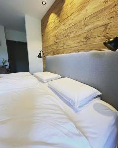 two white beds in a bedroom with a wooden headboard at Pension Kitty in Pörtschach am Wörthersee