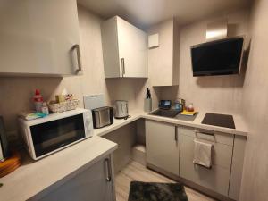 eine kleine Küche mit weißen Schränken und einer Mikrowelle in der Unterkunft Ferienwohnung Gohlke in Stralsund