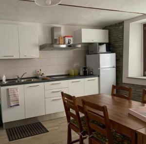 a kitchen with white cabinets and a wooden table at Il cortile dei frutti selvatici in Santo Stefano Belbo