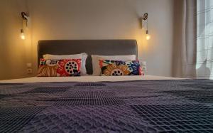 a bedroom with a large bed with colorful pillows at Maistros Suites - Péra in Skopelos Town