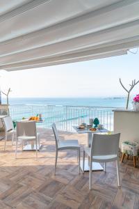 eine Terrasse mit einem Tisch, Stühlen und Meerblick in der Unterkunft BellaVista in Taormina