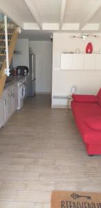uma sala de estar com um sofá vermelho e uma cozinha em MAISONNETTE AU BORD DE L ETANG em Leucate