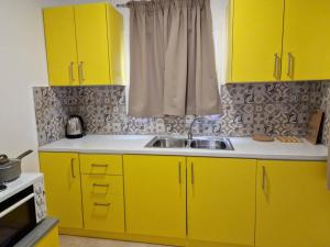 - une cuisine avec des placards jaunes et un évier dans l'établissement SOLYMAR PRIVE, à Archangelos