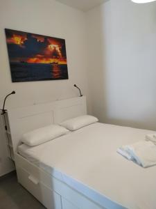 un letto bianco in una stanza con una foto sul muro di NOVELLA DEL MAR prima fila dal mare a Grottammare
