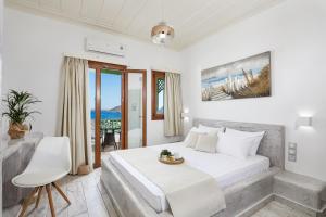 a white bedroom with a bed and a table at Agnadi studios in Maltezana