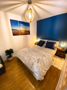 - une chambre avec un grand lit et un mur bleu dans l'établissement Cozy 2 pièces AUX PORTES DE PARIS !, à Issy-les-Moulineaux