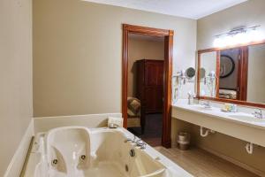 a bathroom with a tub and a sink and a mirror at Carlisle Inn Walnut Creek in Walnut Creek