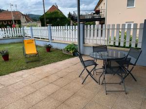 2 stoelen en een glazen tafel op een patio bij Au Paradis de la Rivière Joyeuse in Willer-sur-Thur