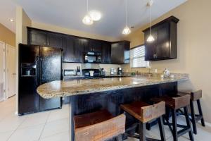 a kitchen with black cabinets and a counter with stools at Kingfisher in South Padre Island