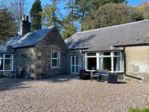 a stone house with chairs and a table in front of it at Peaceful woodland cottage with fireplace in Elie